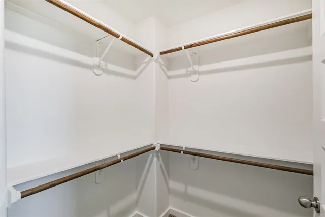 an empty room with chandelier fan and windows