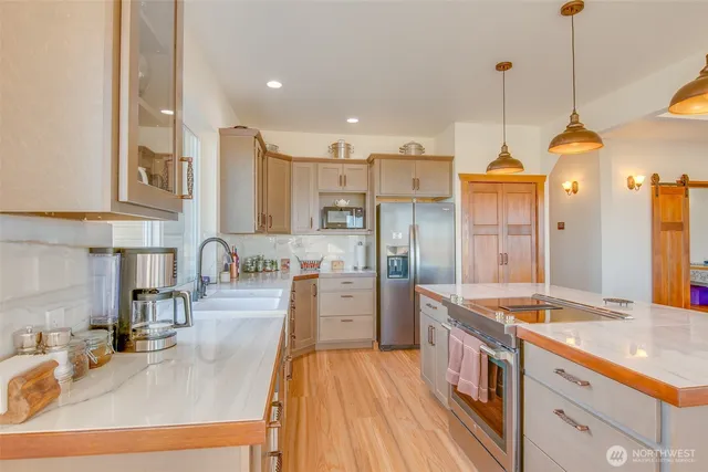 a kitchen with stainless steel appliances granite countertop a stove a refrigerator a sink a dining table and chairs with wooden floor