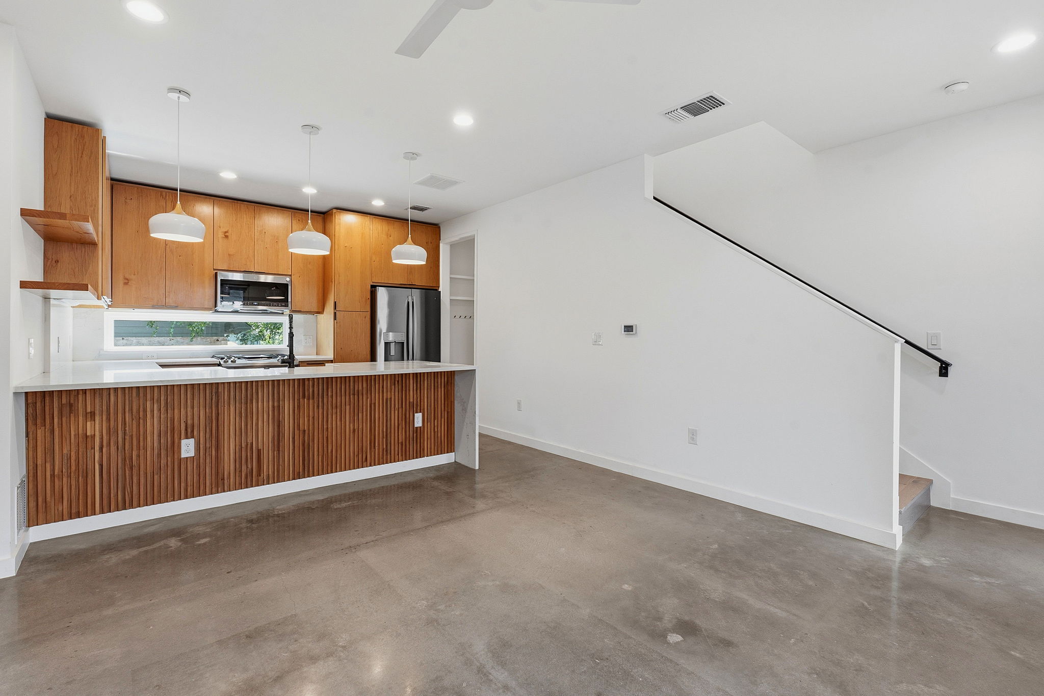 1707 Deloney Street, Unit 2 Austin, TX 78721 - Photo 2 of 26 A well-lit kitchen with sleek wooden cabinetry and concrete floors, seamlessly connecting to an open living area.