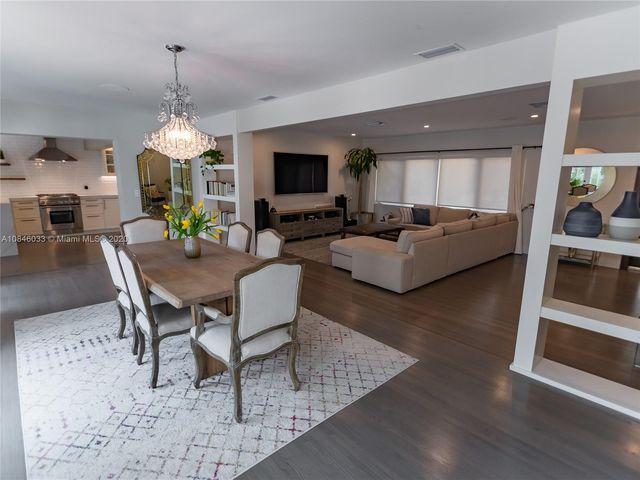 a dining room with wooden floor a chandelier a glass table and chairs