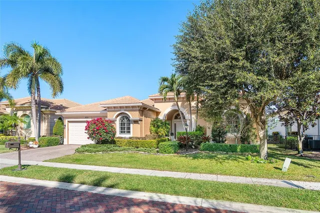 a front view of a house with a yard and palm trees