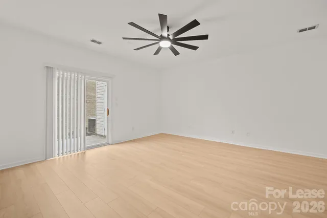 a view of empty room with wooden floor and ceiling fan
