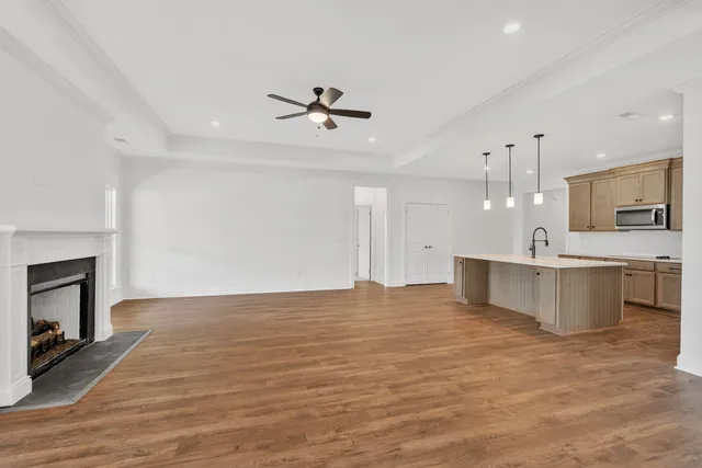 an empty room with wooden floor fireplace and windows