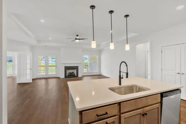 a view of an empty room with wooden floor and fan