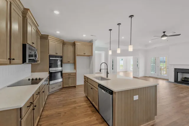 a kitchen with stainless steel appliances granite countertop a sink a stove and a wooden floors