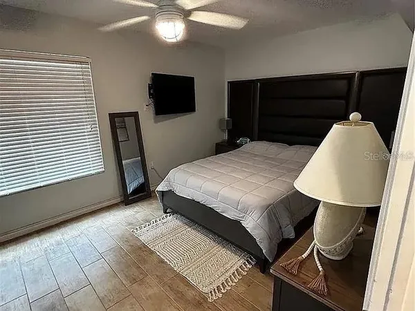a bedroom with a bed a mirror on dresser and a window