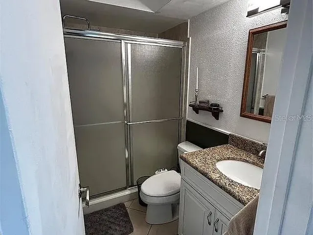 a bathroom with a granite countertop toilet and a sink