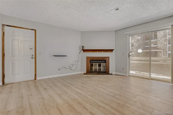 a view of empty room with wooden floor and fireplace