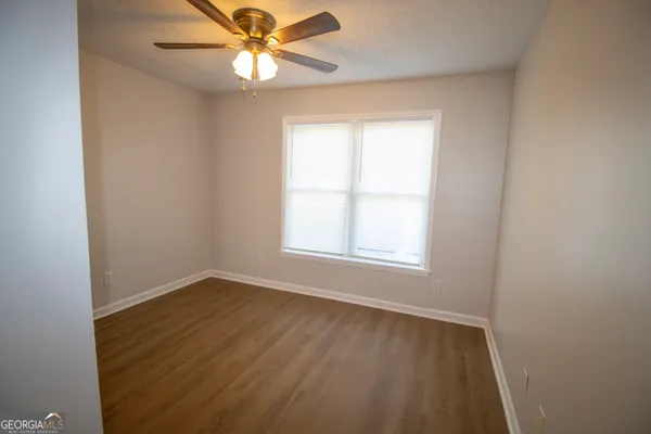 an empty room with a window and a fan