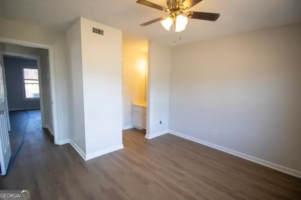 an empty room with wooden floor fan and windows
