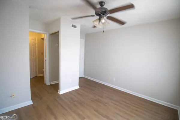 an empty room with wooden floor and ceiling fan