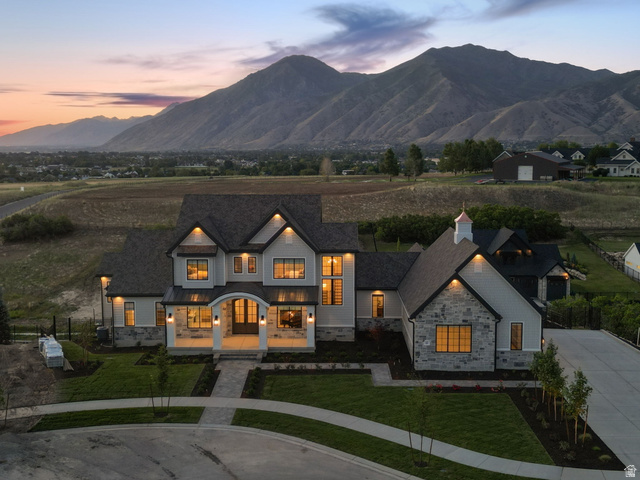 115 East Hidden Ridge Lane, Unit 42 Mapleton, UT 84664 - Photo 93 of 103 Contemporary residence featuring a prominent mountain backdrop, multi-gabled roofline, mixed material facade with stone and siding, a covered front porch, and a well-landscaped front yard with a defined walkway