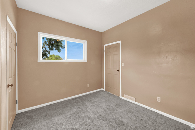 716 East Factory Street Garland, UT 84312 - Photo 21 of 30 Neutral tone walls with white trim, gray carpet flooring, and a white-framed window