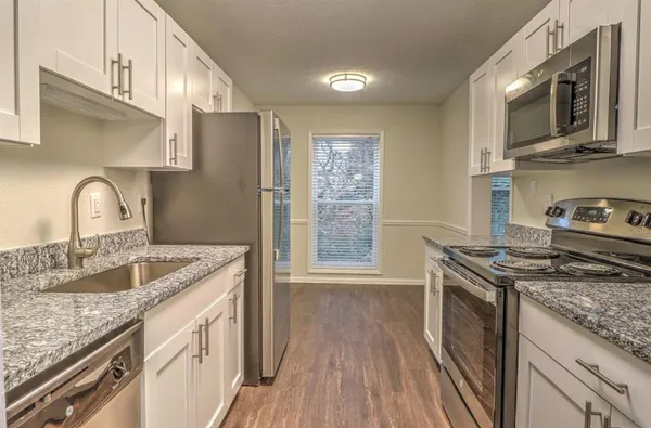 a kitchen with granite countertop a sink stove and refrigerator