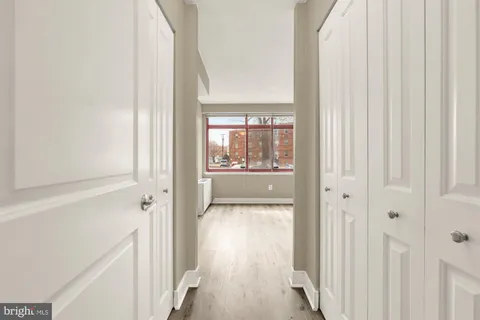 a view of a hallway with wooden floor and a bathroom