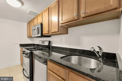 a kitchen with granite countertop a sink a stove and cabinets