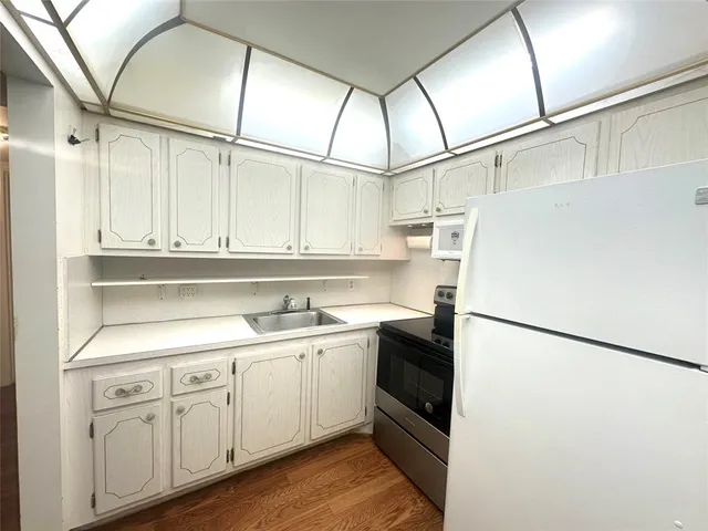 a view of a kitchen with wooden floor and electronic appliances
