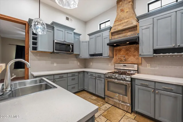 a kitchen with stainless steel appliances granite countertop a sink a refrigerator and a stove