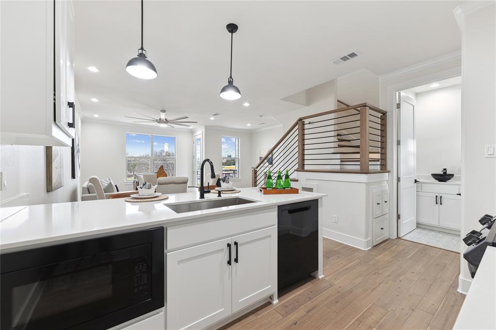 3230 Elihu Street, Unit 5 Dallas, TX 75210 - Photo 2 of 17 a kitchen with a sink dishwasher and white cabinets with wooden floor