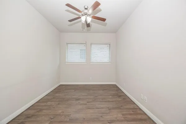 an empty room with wooden floor and a ceiling fan