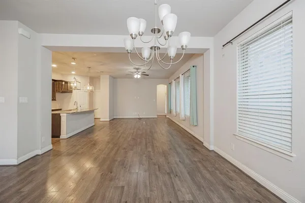 a view of a hallway with wooden floor and chandelier