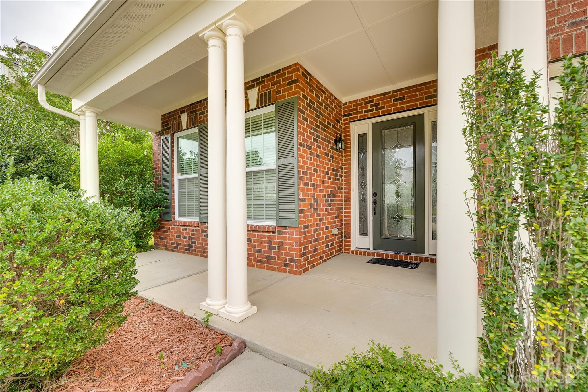 4025 Orchid Way Tega Cay, SC 29708 - Photo 3 of 44 a view of a brick house with potted plants and a table and chairs