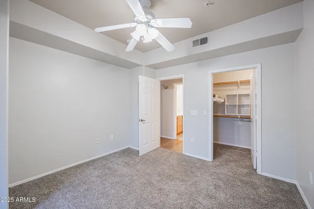 an empty room with a ceiling fan and carpet