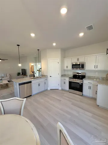 a large white kitchen with kitchen island a sink a stove a oven a dining table and chairs