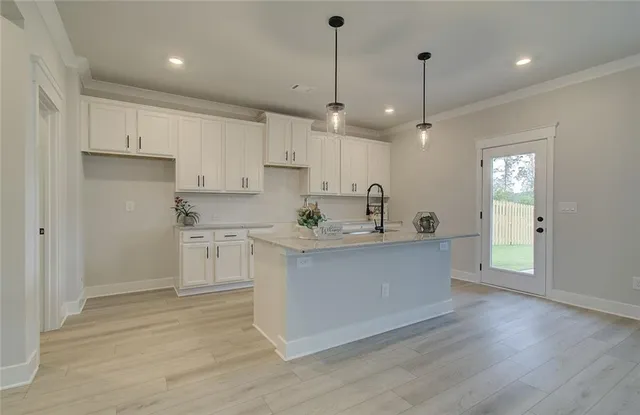 a kitchen with stainless steel appliances granite countertop a sink a stove a refrigerator and white cabinets with wooden floor