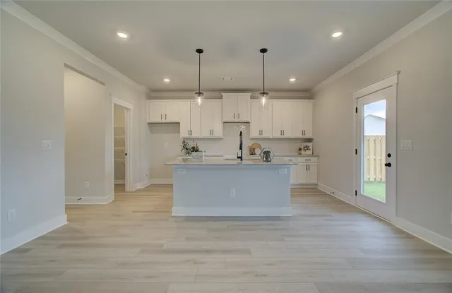 a view of kitchen with kitchen island white cabinets and stainless steel appliances