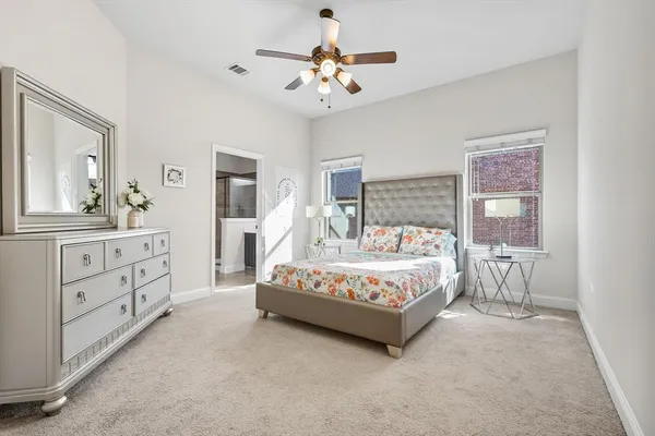 a spacious bedroom with a bed a chandelier and a dresser