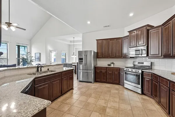 a kitchen with stainless steel appliances granite countertop wooden cabinets a stove a sink and a oven
