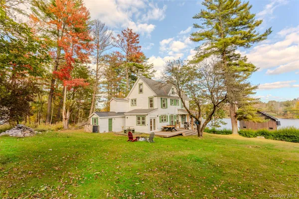 a view of a white house with a big yard and large trees