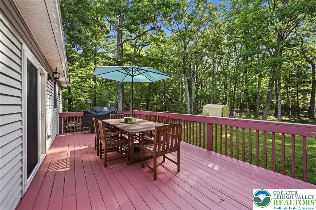 128 Chestnut Street Dingmans Ferry, PA 18328 - Photo 30 of 43 An inviting deck off the kitchen offers a serene outdoor dining area, enveloped by lush, mature trees.