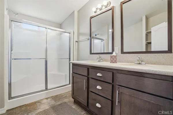 a bathroom with a granite countertop sink a mirror and a shower