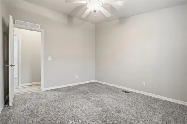 an empty room with a ceiling fan and window