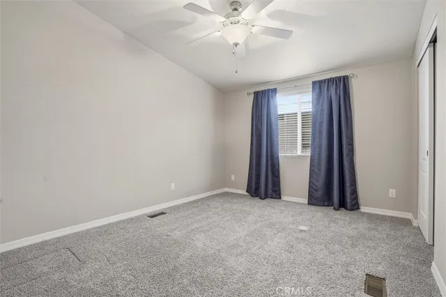 an empty room with a ceiling fan and window