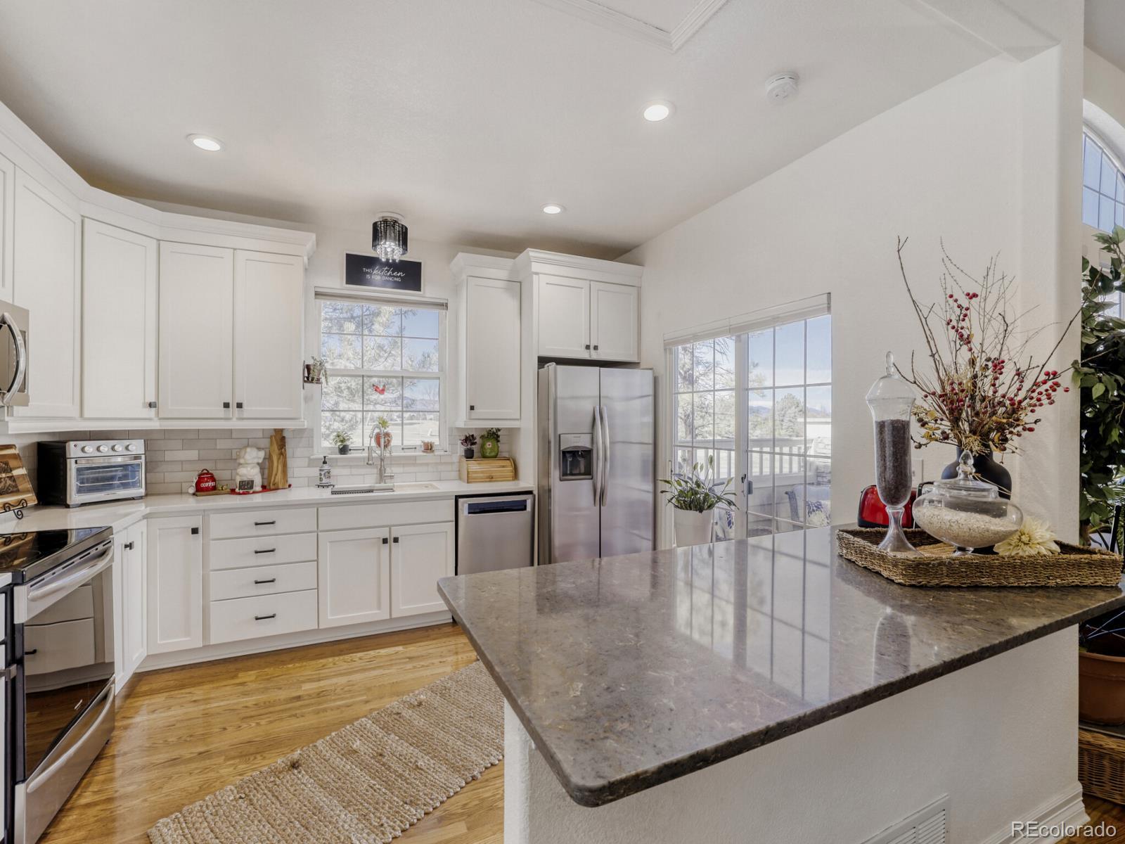 8893 Tappy Toorie Circle Highlands Ranch, CO 80129 - Photo 8 of 36 a kitchen with stainless steel appliances granite countertop a sink dishwasher stove and white cabinets next to a window