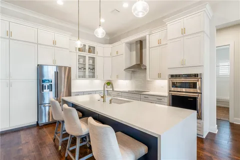 a kitchen with stainless steel appliances granite countertop a stove a refrigerator a sink a dining table and chairs with wooden floor