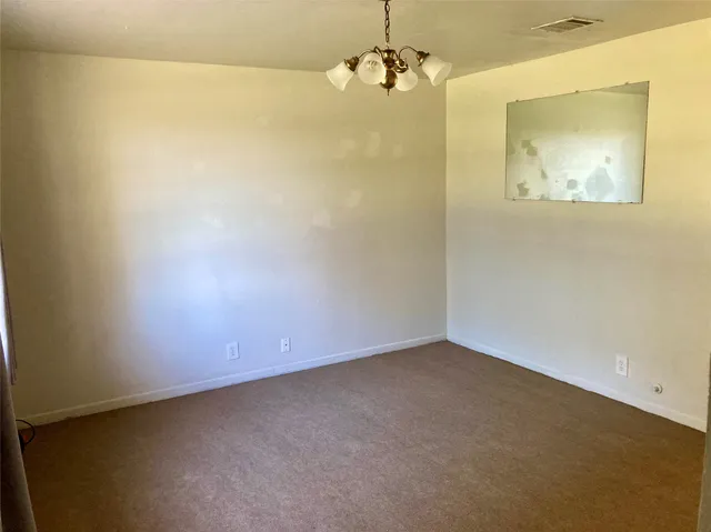 an empty room with a chandelier fan and a wooden floor
