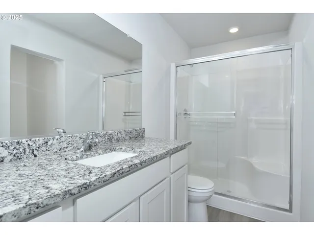 a bathroom with a granite countertop sink toilet a mirror and shower