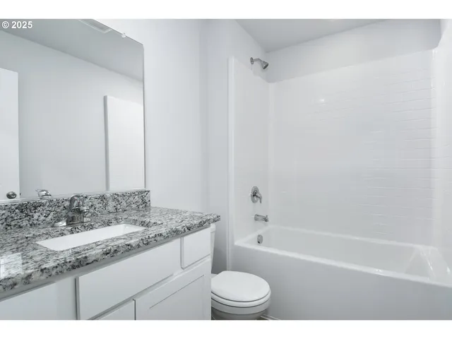 a bathroom with a granite countertop sink toilet mirror and bathtub