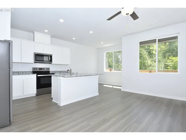 a view of kitchen with granite countertop stainless steel appliances and wooden floor