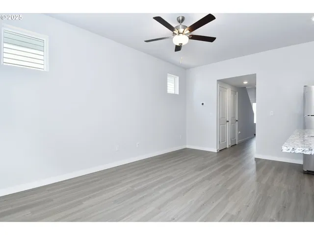 an empty room with wooden floor and a ceiling fan