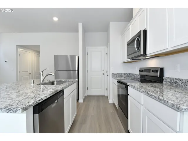 a kitchen with stainless steel appliances granite countertop a sink stove and refrigerator