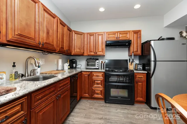 a kitchen with stainless steel appliances granite countertop a stove refrigerator and a sink