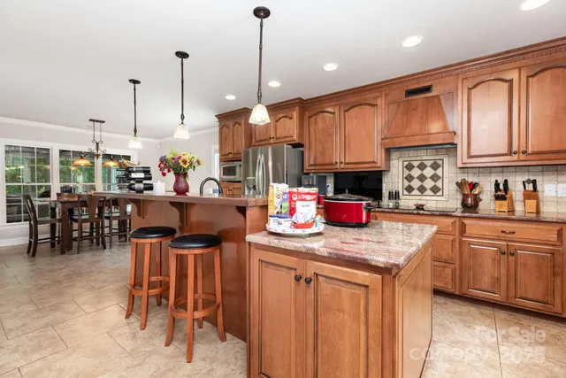 a kitchen with stainless steel appliances granite countertop dining table chairs sink and cabinets
