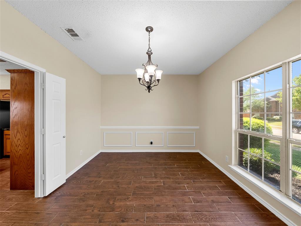 741 Aspen Court Allen, TX 75002 - Photo 12 of 40 Dining room with hanging lights, wood finish tile floors, a decorative wall, and a wainscoted wall