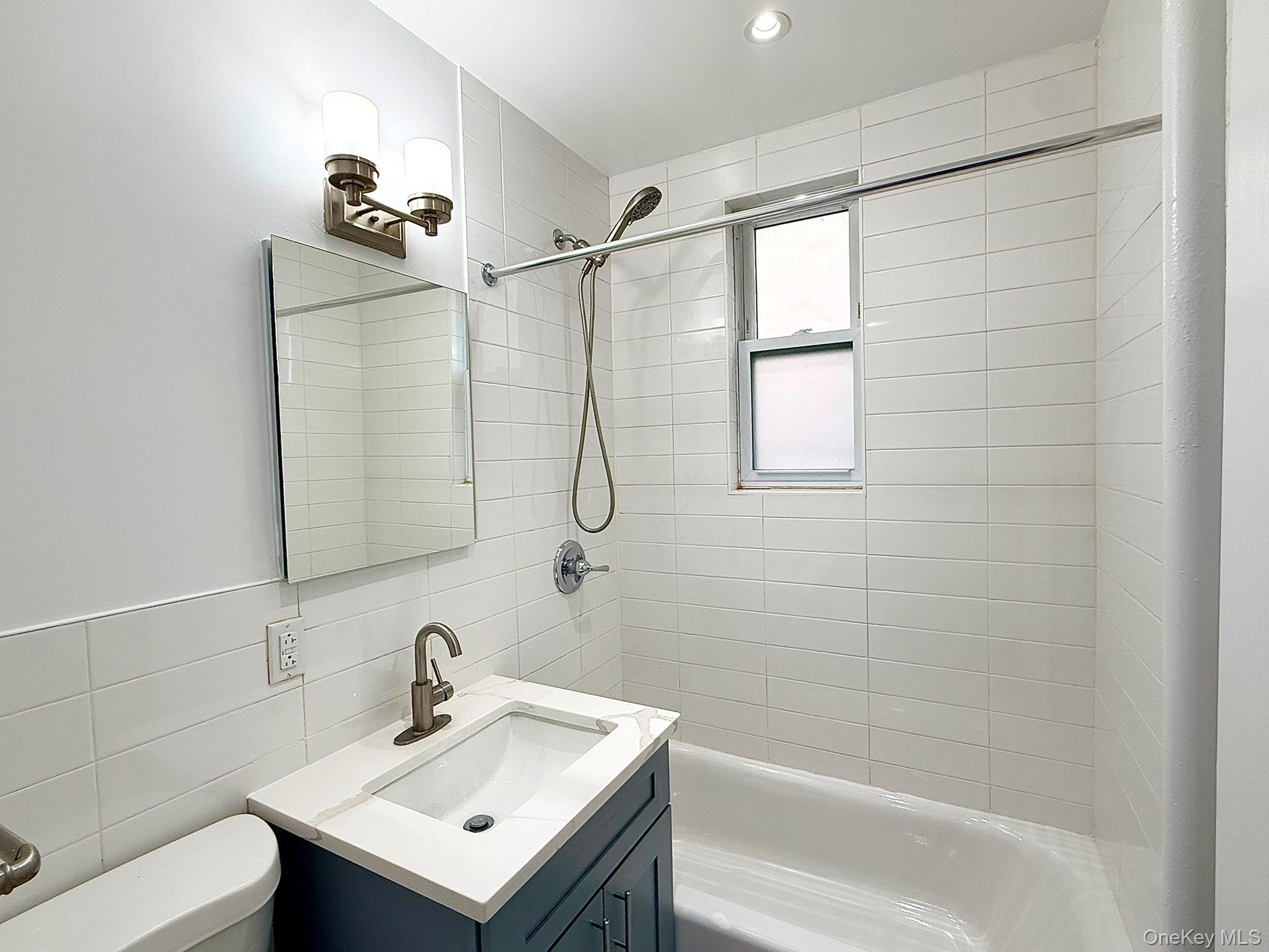 47-48 43rd Street, Unit 2F Queens, NY 11377 - Photo 27 of 29 a bathroom with a sink mirror and a bathtub