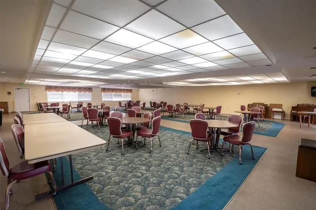 a living room with lots of tables a large window and chairs